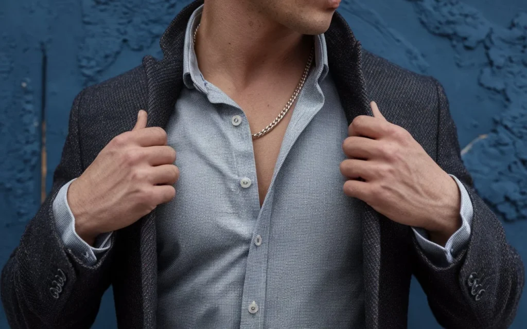 A man wearing a sterling silver chain necklace with a button-up shirt and blazer.